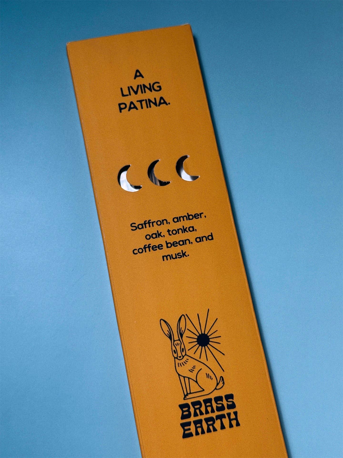 Brass Earth Orange product packaging with black text and branding on a blue background