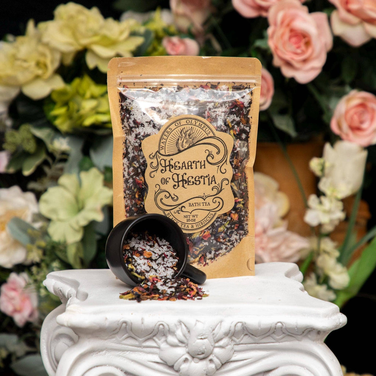 Bath tea packaging with a black mug of bath tea on a decorative stand with flowers in the background