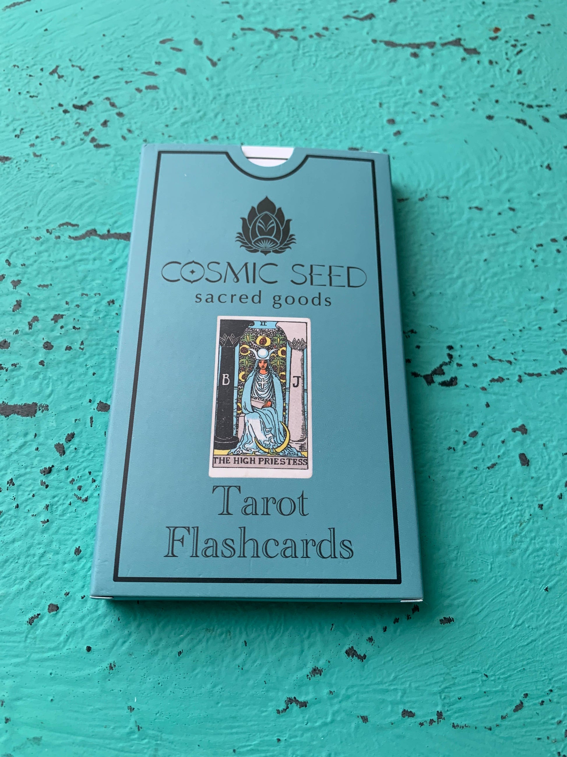 Box of Cosmic Seed Tarot Flashcards on a textured teal surface
