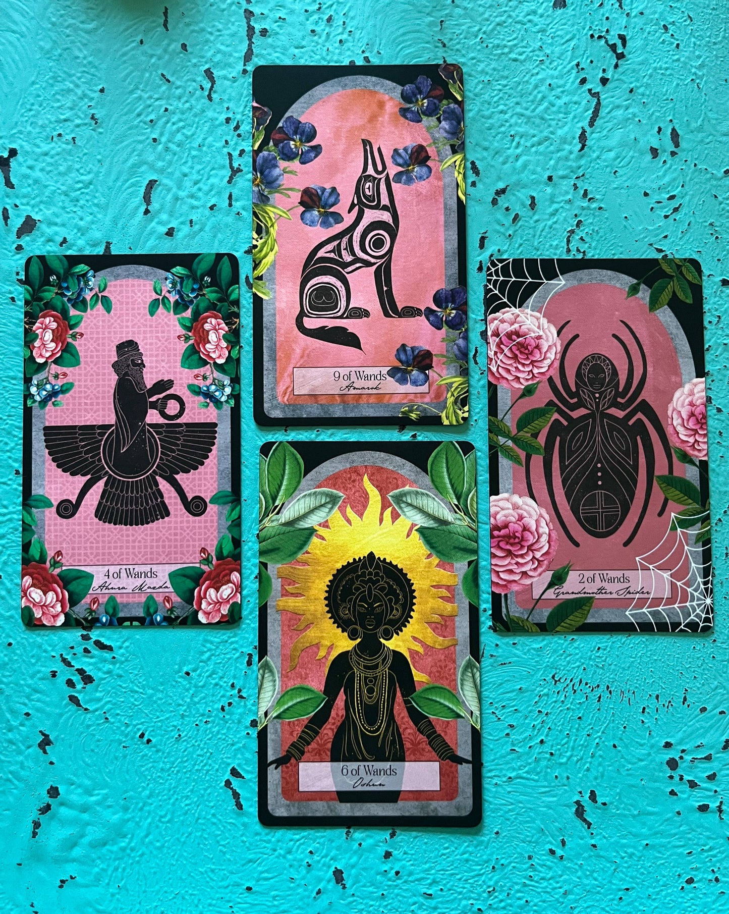 Four tarot cards with black silhouettes on a pink background against a blue textured wall.