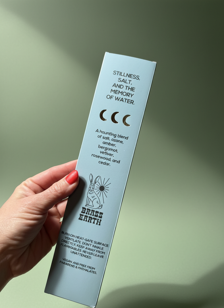 Hand holding a product packaging with text and branding on a light green background