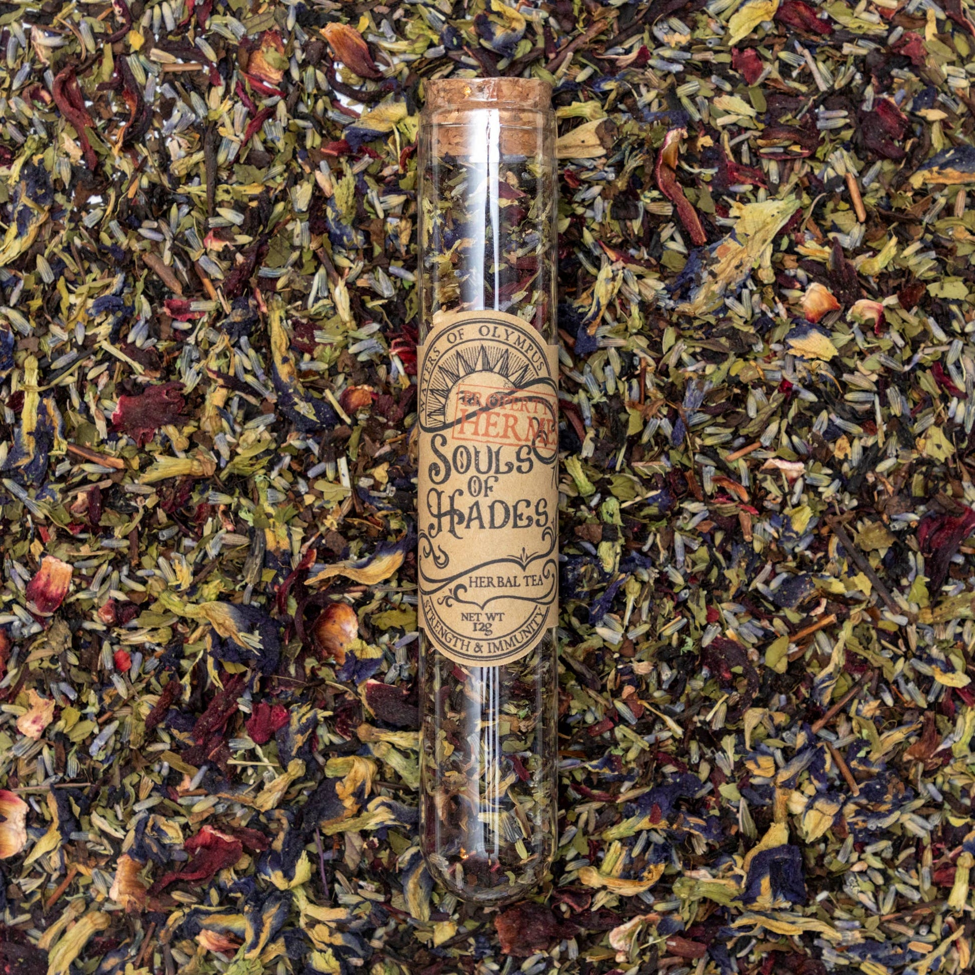 Tea leaves with a glass tube labeled 'Spirits of Olympus' on a bed of tea leaves.