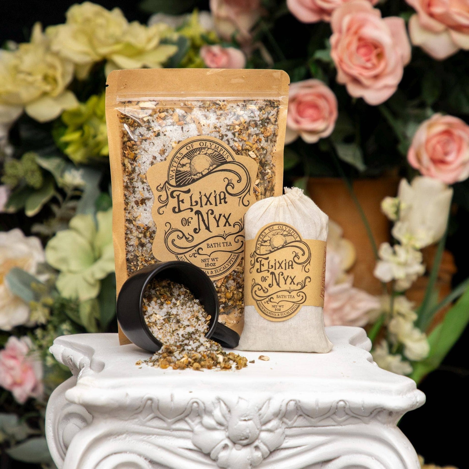 Elixir of Nyx bath tea packaging with a black cup on a decorative stand with flowers in the background
