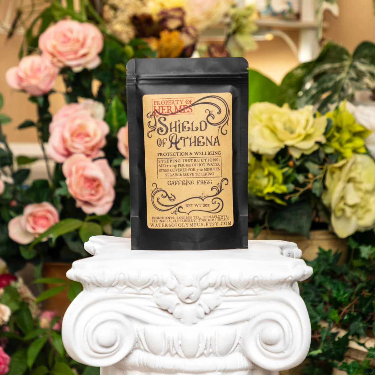 Black packaging with decorative text on a white pedestal against a floral background