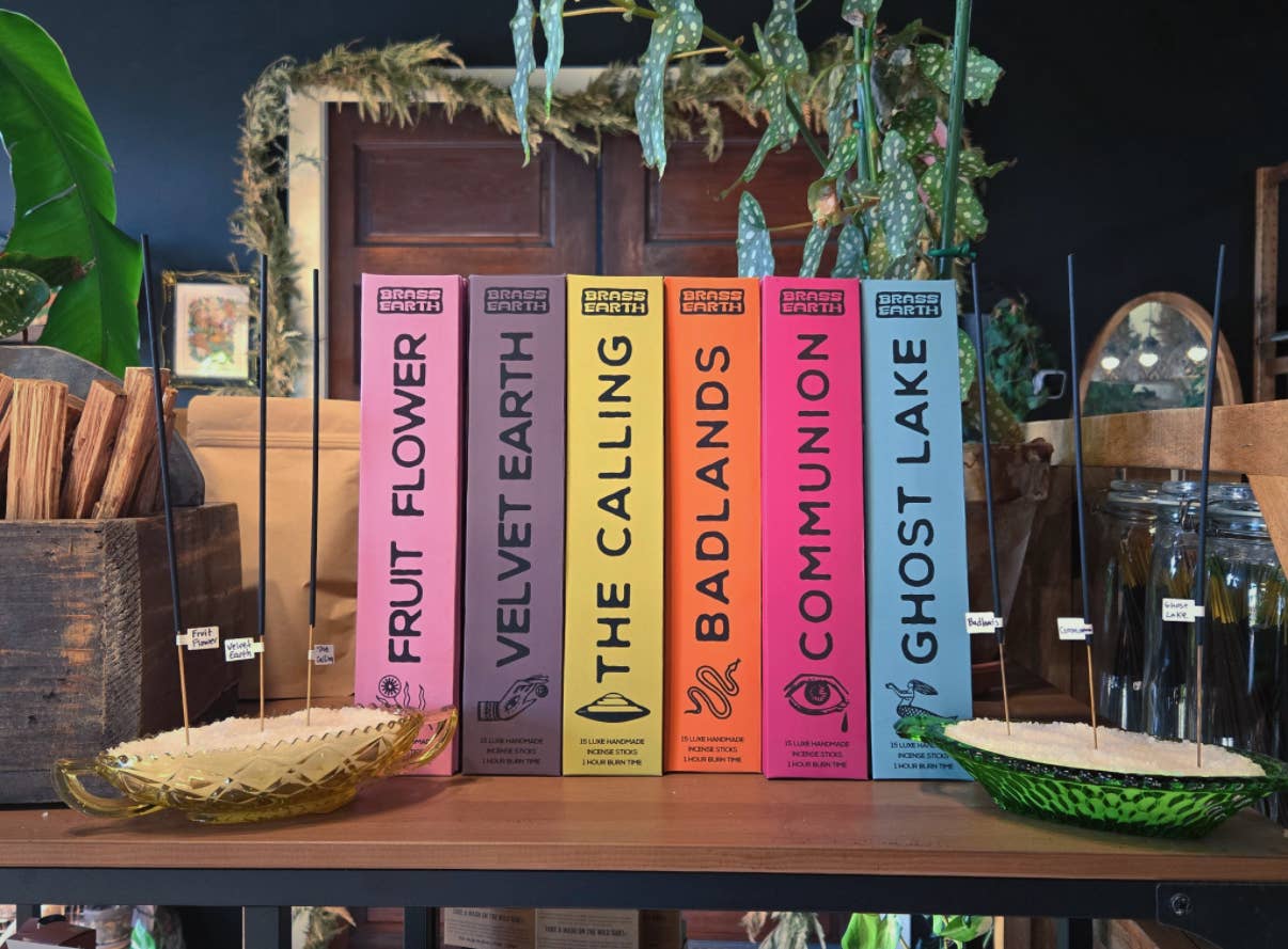 Row of incense with colorful boxes on a wooden table, surrounded by decorative elements.