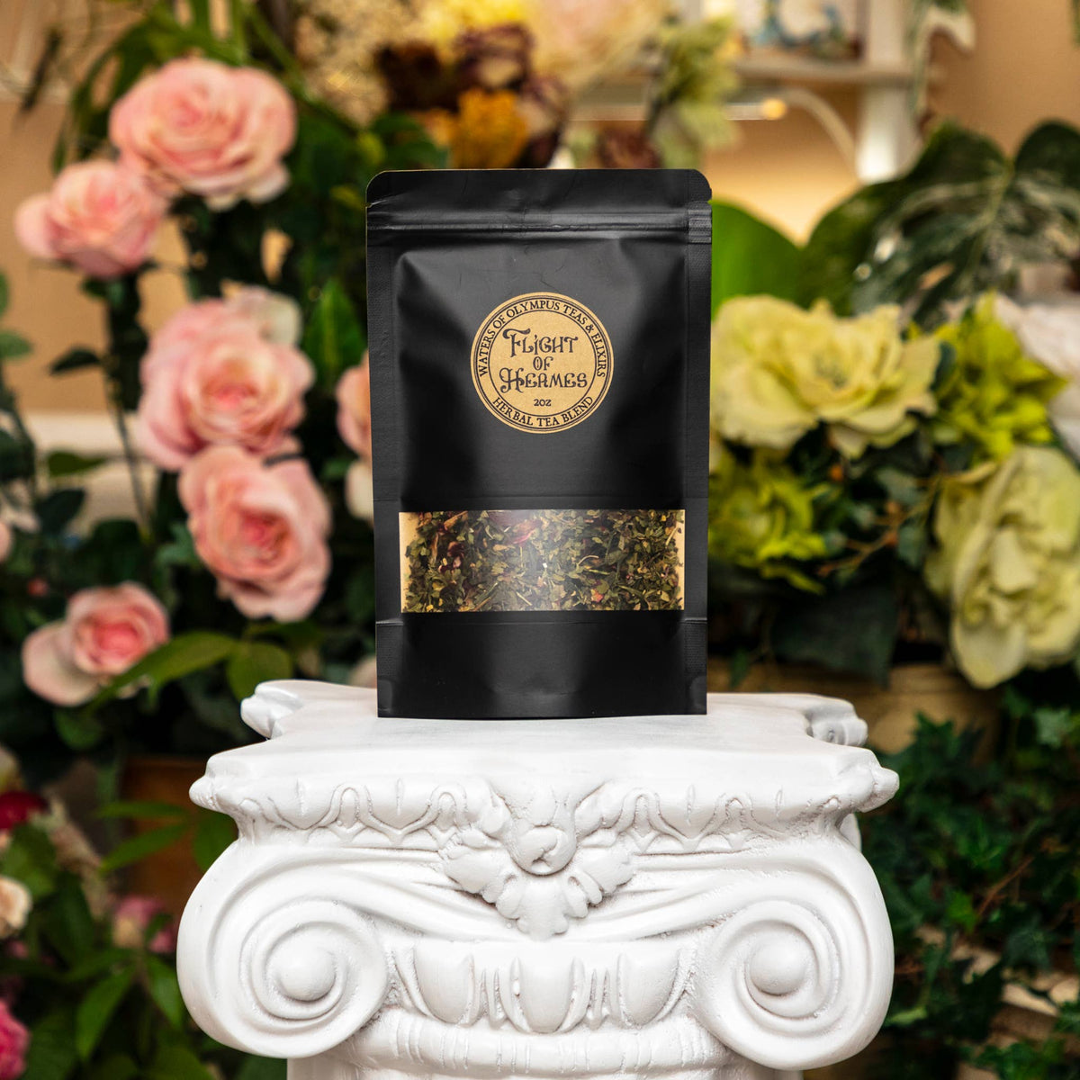 Black tea package on a decorative white pedestal with flowers in the background