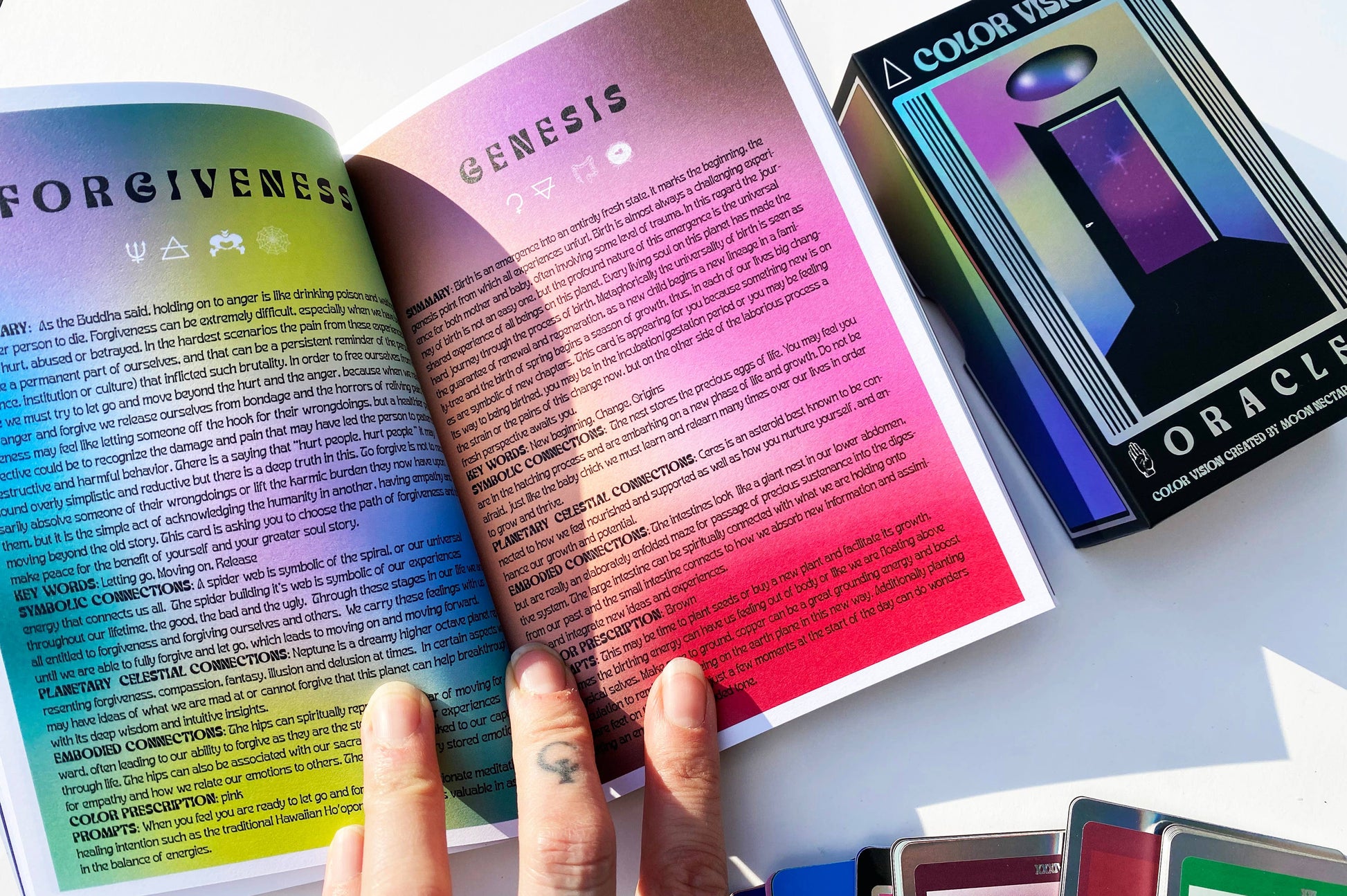 Color Vision Oracle guidebook and deck with a hand holding open pages showing a gradient of colors.