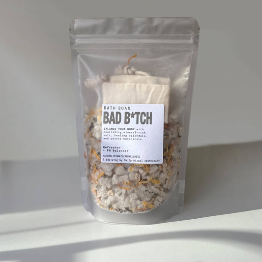 A pouch labeled 'BATH SMOKE BAD B*TCH' filled with dried botanicals and sea salt for bath making.