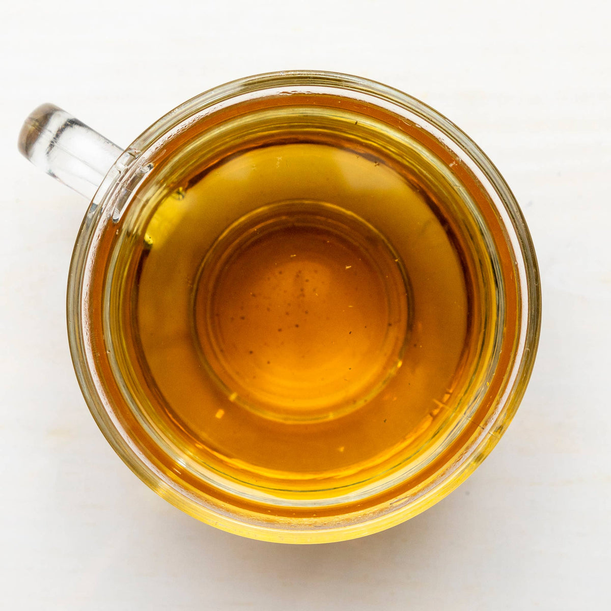 Clear glass mug filled with amber tea on a white background