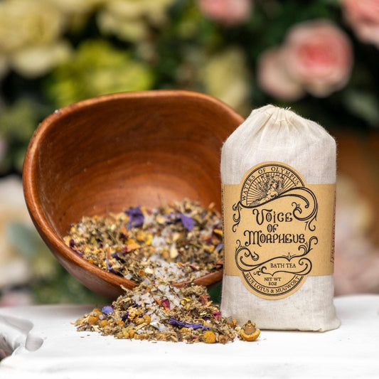 Bag of 'Voice of Morpheus' bath tea with a wooden bowl of dried herbs on a floral background