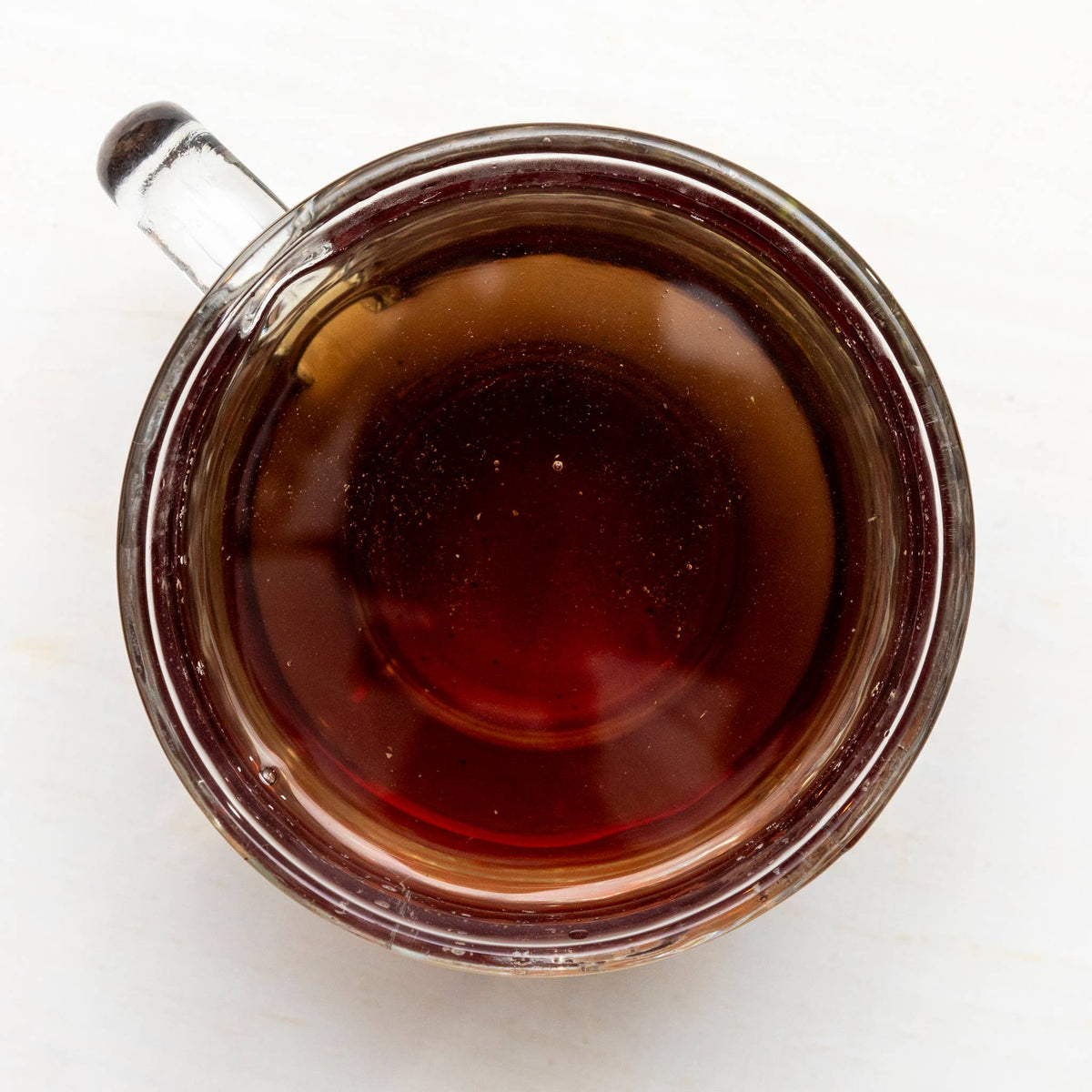 Glass cup filled with dark tea on a white background